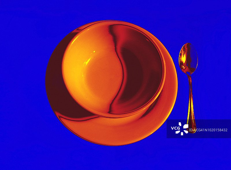 转换图像的白色陶瓷盘子和碗和银勺子到金色的橙色在蓝色的背景图片素材
