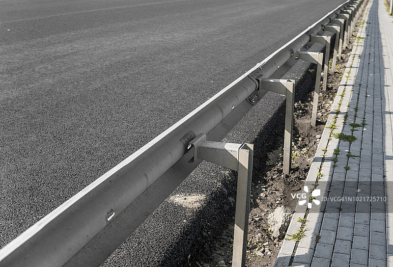 特写一层新的沥青在道路建设与人行道道路和保险杠。图片素材