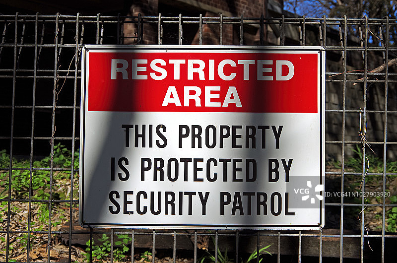 铁丝网围栏上写着“禁区:这处房产受到保安巡逻的保护”图片素材