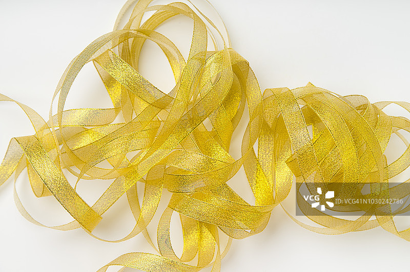 闪亮的金色丝带缠绕在白色背景的螺旋图案。文本或公告的背景图片素材