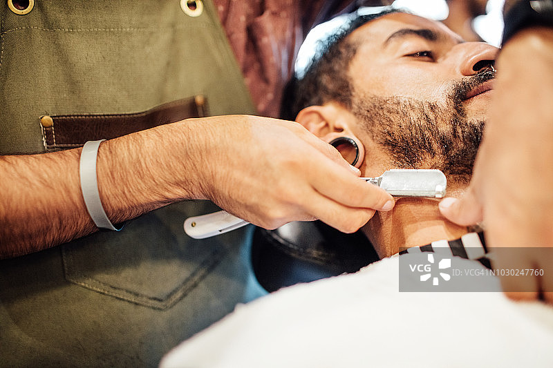 理发师在理发店用直刮胡刀刮胡子图片素材