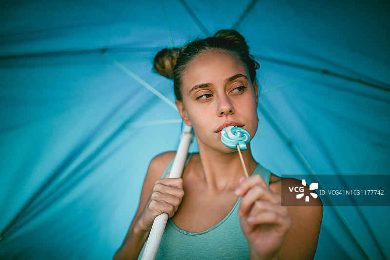 可爱的少女吃棒棒糖和享受海滩时间的肖像图片素材