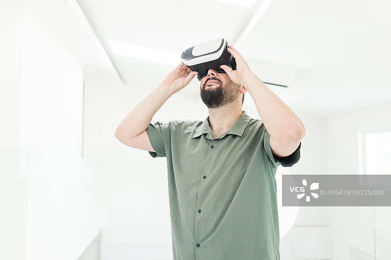 成年男子使用虚拟现实头盔在未来的房间图片素材