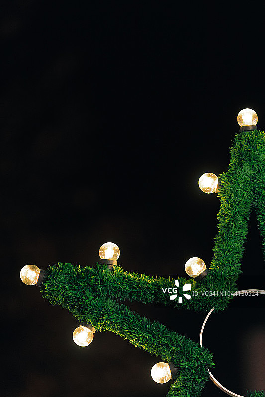 特写的圣诞街道装饰灯和松木花环。黑色背景图片素材