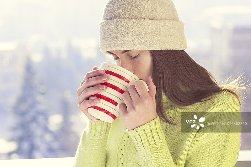 年轻女子与一杯热饮在雪天的冬天图片素材