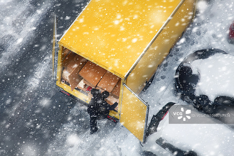 在下雪的时候，黄色的卡车停在结冰的城市街道上图片素材