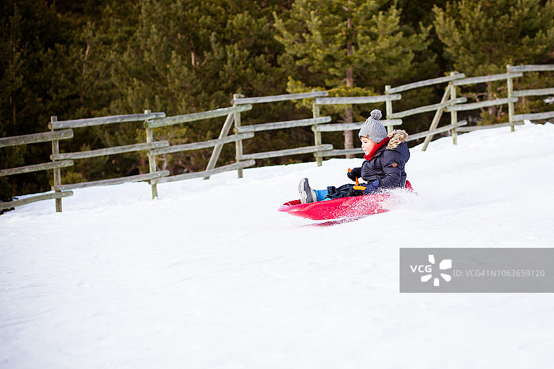 一个男孩用雪橇拉下一座雪山图片素材