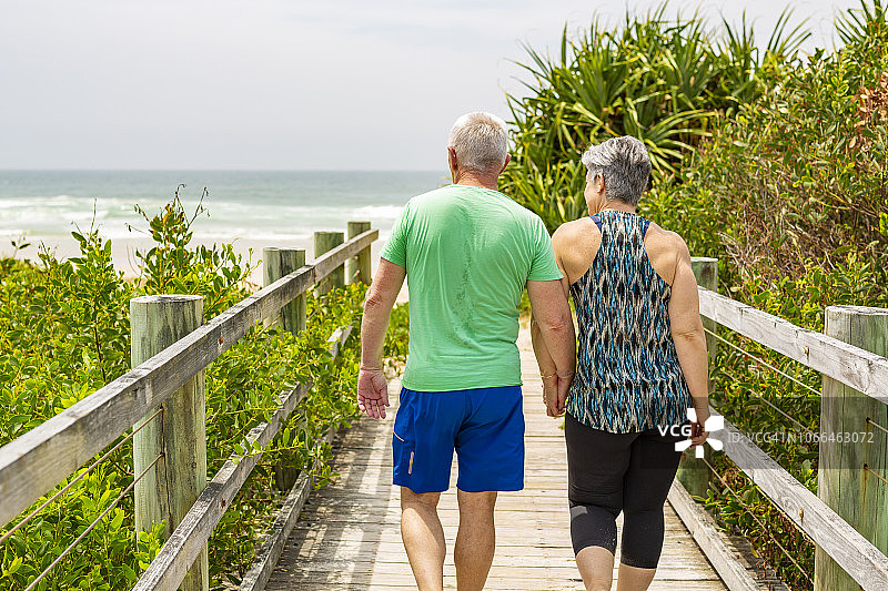 一对老年夫妇在海滩的木板路上散步图片素材