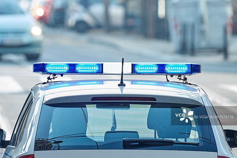 在交通/城市环境的犯罪现场上开着蓝色灯的警车。图片素材