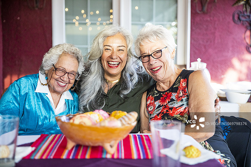 三个微笑着吃甜面包的墨西哥女人图片素材