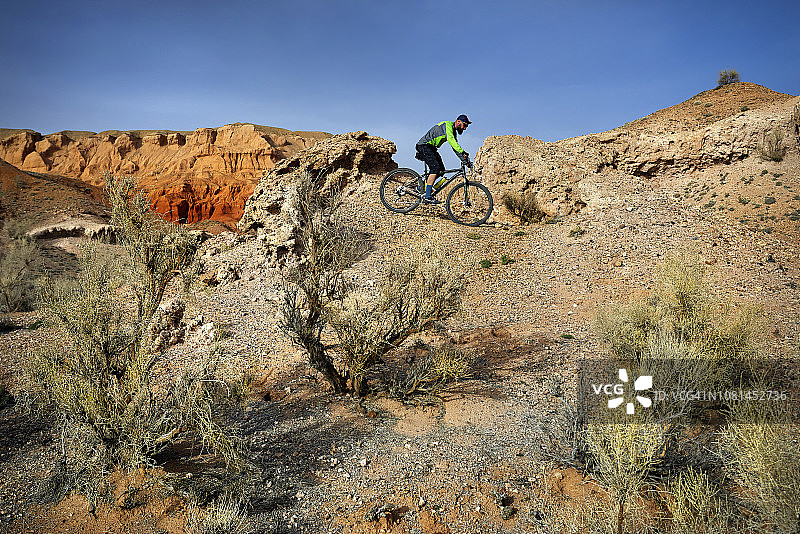 在沙漠骑山地自行车的徒步旅行者的侧视图图片素材