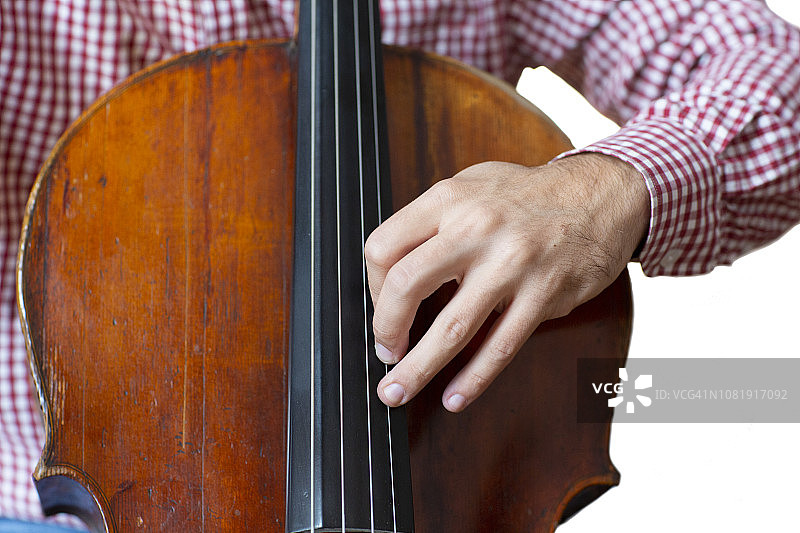 大提琴手演奏大提琴手靠近管弦乐器孤立的图像在白色的背景。图片素材