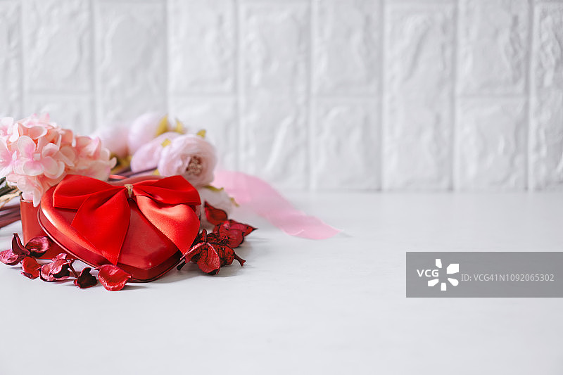 红色心形礼盒，花和干花瓣在白色的背景图片素材