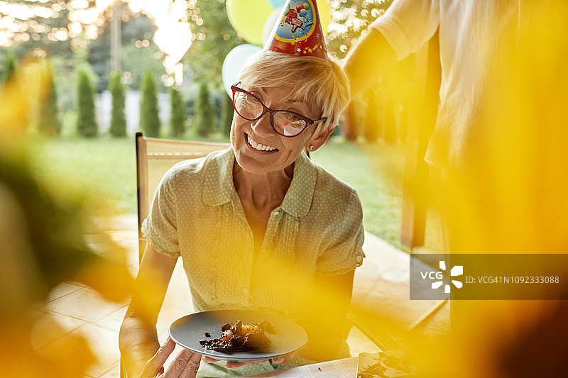 在生日游园会上，微笑着的成熟女人拿着盛有蛋糕的盘子图片素材