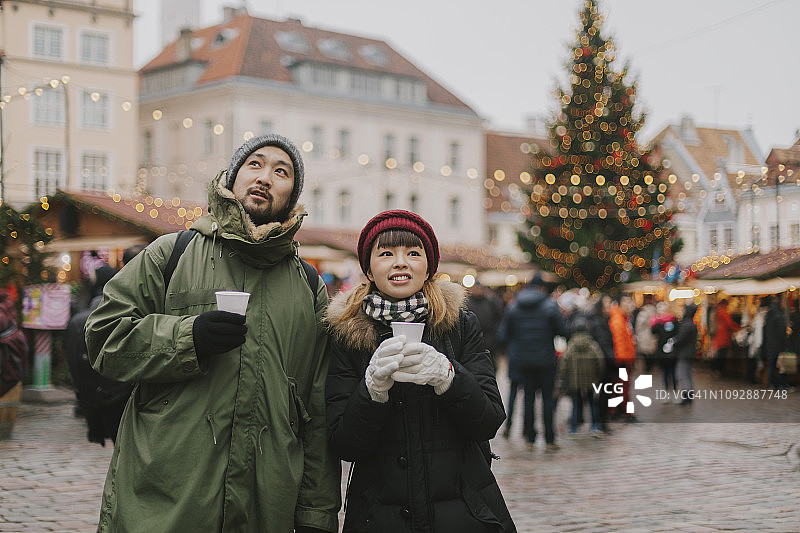 一对情侣在圣诞市场散步，喝着热红酒图片素材