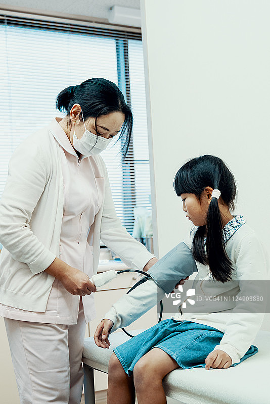 中年女性护士测量一个年轻女孩的血压图片素材