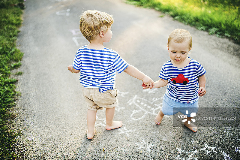 蹒跚学步的小男孩和他的小妹妹在户外玩图片素材