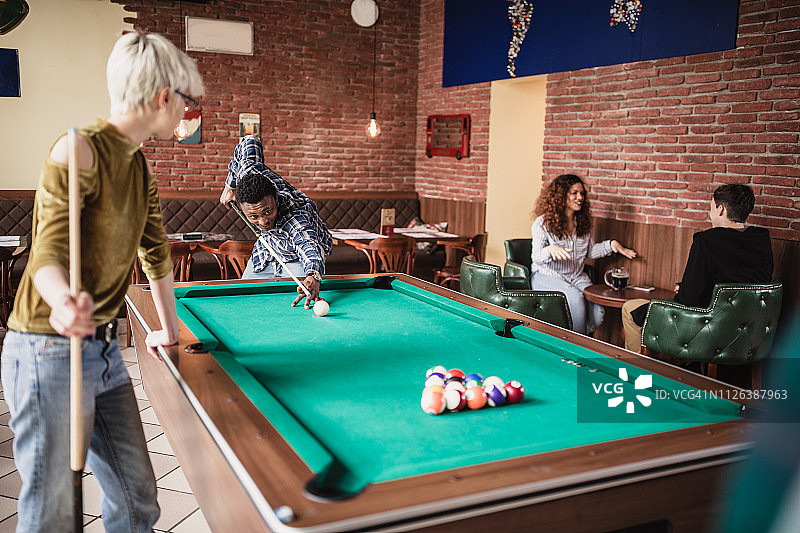 一群朋友在酒吧里玩斯诺克，一起玩乐。图片素材