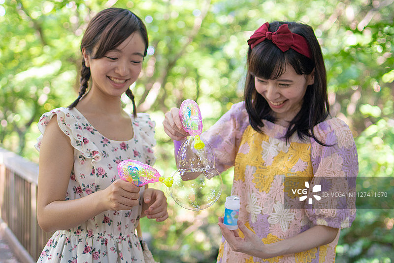 年轻女子在绿色森林里玩肥皂泡图片素材