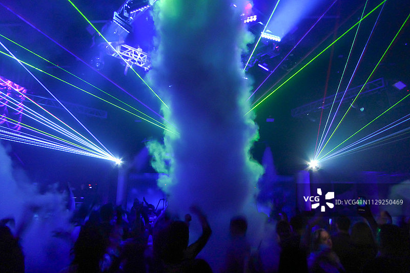 人们在夜店里用烟雾和激光跳舞图片素材