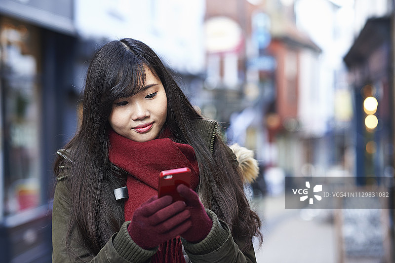 一名年轻女子在城市街道上使用智能手机图片素材