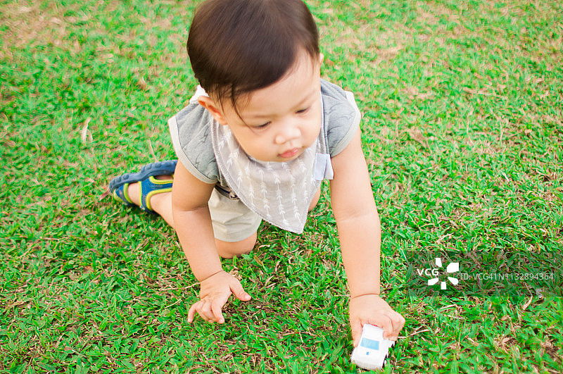 一个小男孩在公园里玩玩具车图片素材
