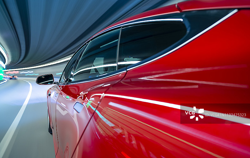 一辆红色的电动汽车在隧道中疾驰。图片素材