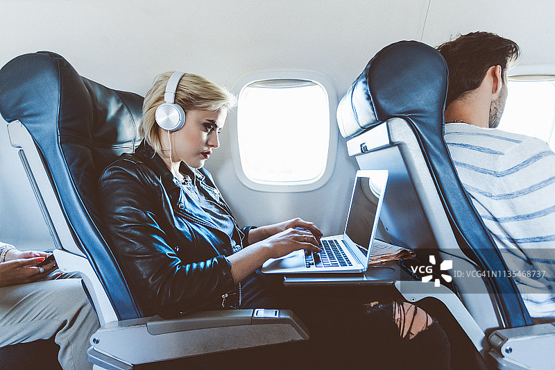 女性旅客在飞机上使用笔记本电脑图片素材