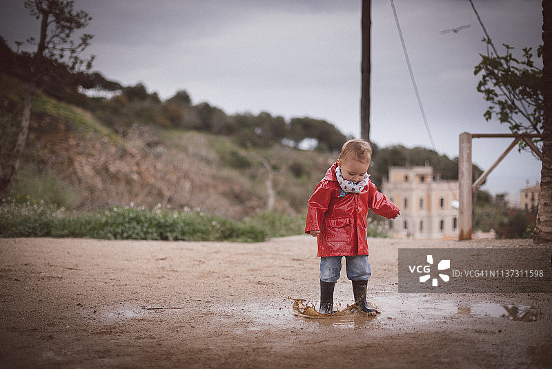 一个男孩在雨天踩水坑图片素材