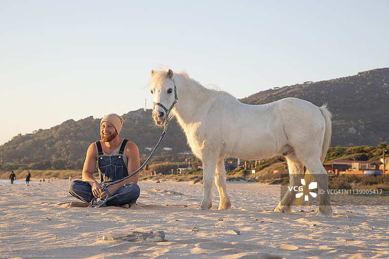 西班牙，塔里法，沙滩上骑着小马的快乐男人图片素材