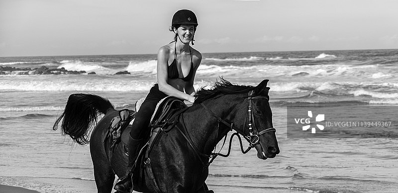 迷人的年轻女子慢跑在海滩上的栗色马穿着比基尼上衣图片素材