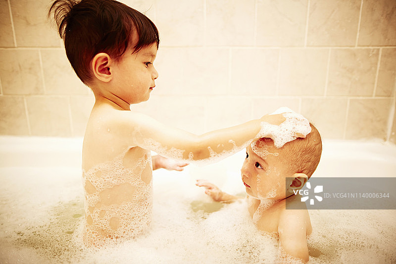 男孩在浴缸里给弟弟洗澡图片素材