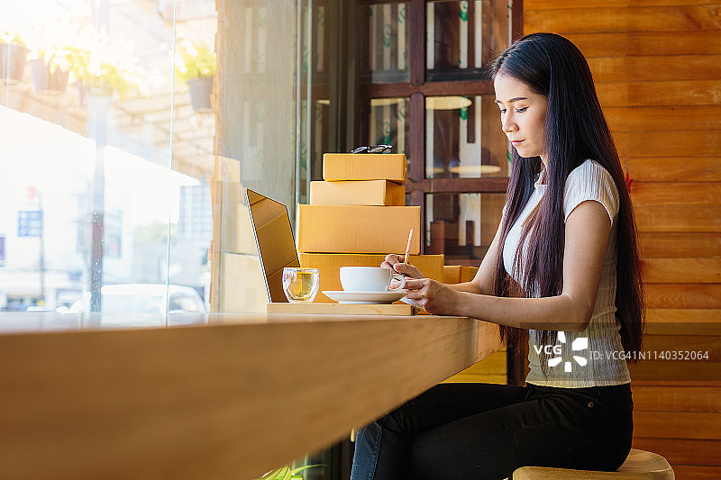 美丽的亚洲女性自由职业者或女商人使用她的笔记本电脑和工作在咖啡店图片素材