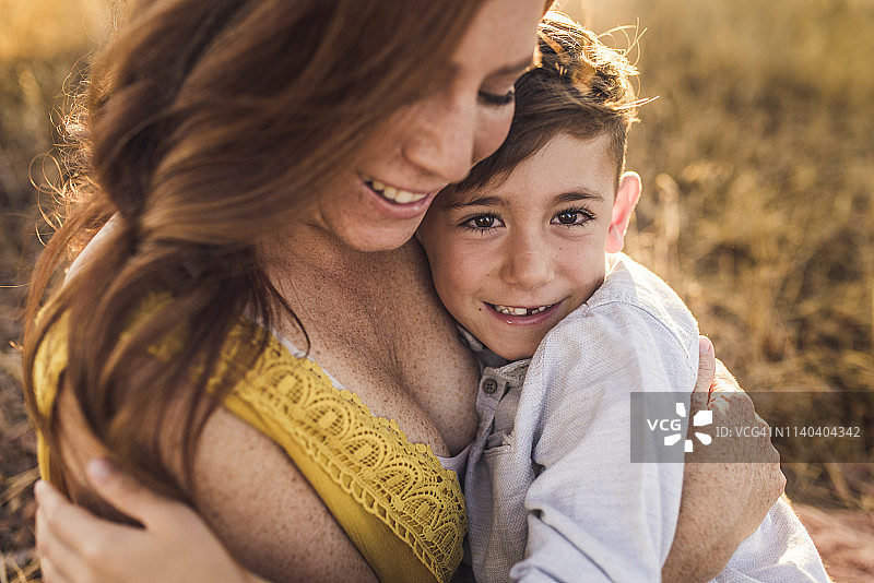 小男孩被微笑的母亲拥抱在加利福尼亚的田地里的特写图片素材