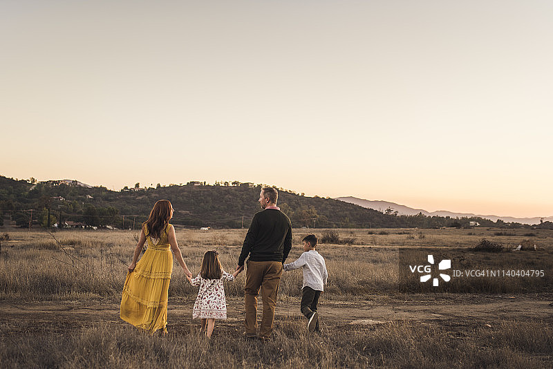 年轻的家庭手牵着手离开加州的田野图片素材