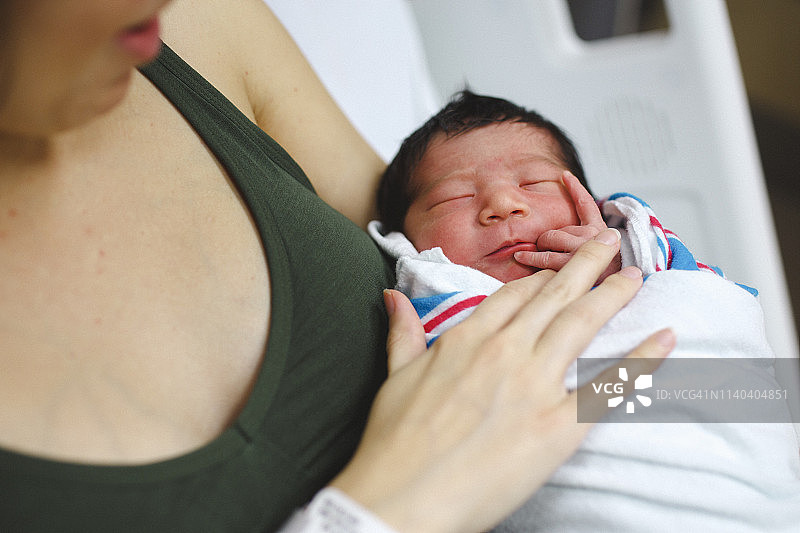 在医院的病床上，一位母亲温柔地抱着她刚出生的女婴图片素材