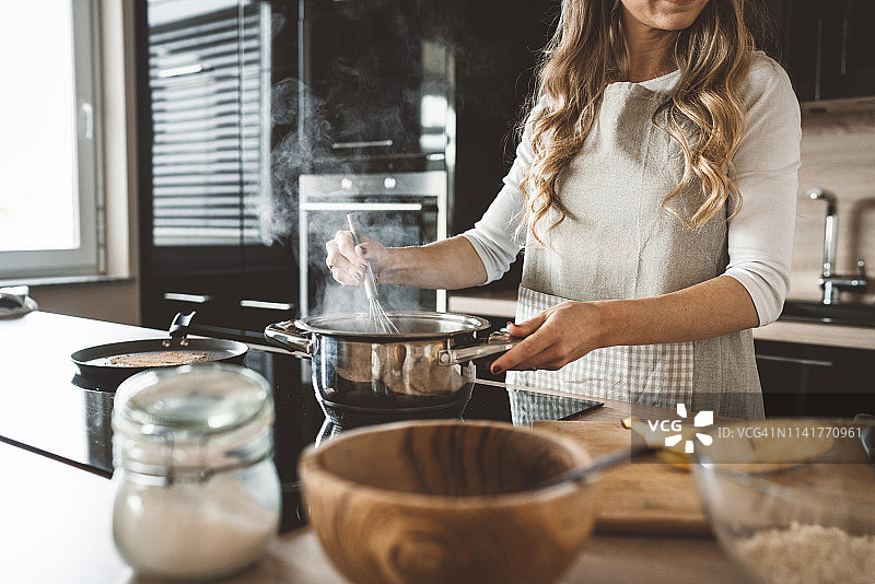一个在现代厨房里煮汤的女人图片素材