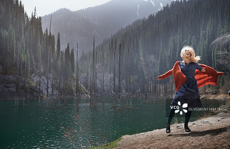 快乐的女人在山上的湖泊和淹没的树木图片素材