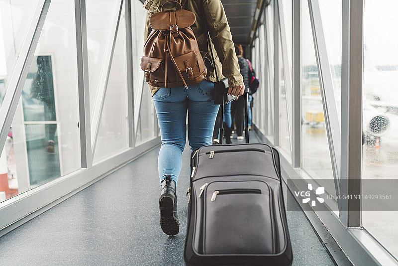 一名年轻女子在登机前拉着手提箱图片素材