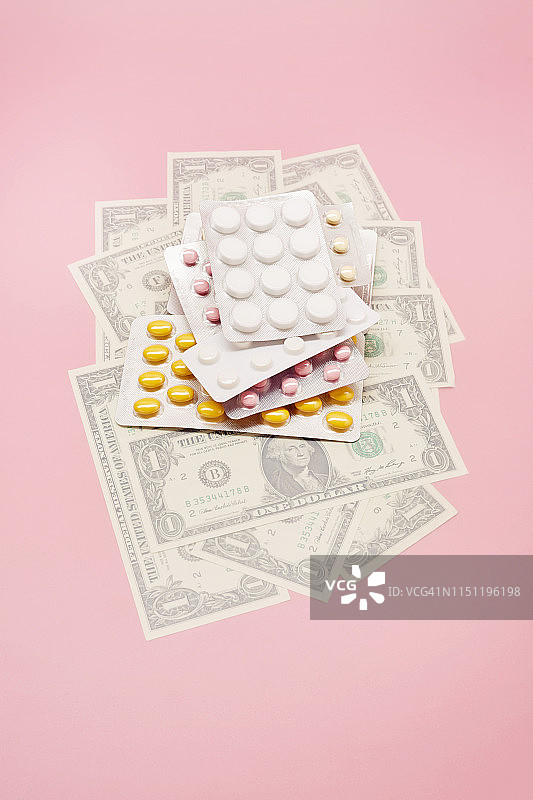 美钞和粉色背景上药丸的泡罩包装的静物图片素材