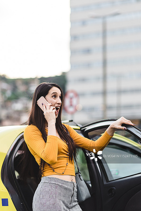 一名年轻女子在车门边用智能手机聊天图片素材