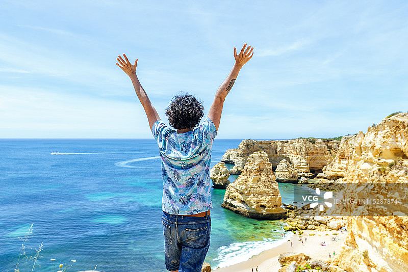 葡萄牙阿尔加维马里尼亚海滩，一名男子举起手臂图片素材