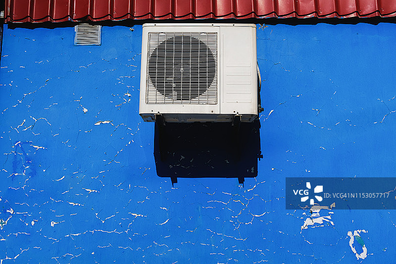 工业通风、空调安装在带有自然缺陷的破旧墙体上。蓝色抽象墙有划痕，裂缝，碎屑，不规则。为文本复制空间。图片素材