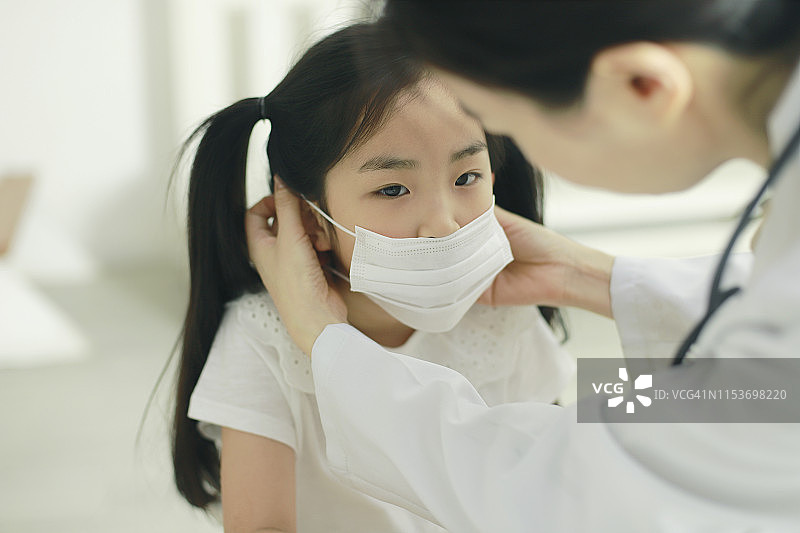 医生给女孩戴上流感口罩图片素材