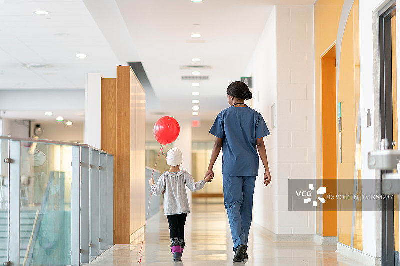 在医院走廊里，孩子用气球牵着医生的手图片素材