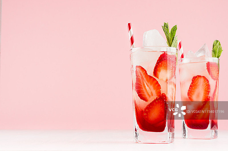 新鲜的冷酒精饮料，草莓酒，切片水果，冰，吸管，薄荷优雅的粉红色背景和白色木板图片素材