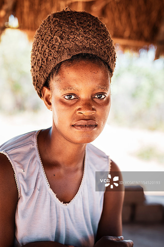一个年轻的非洲妇女坐在小屋下的肖像图片素材