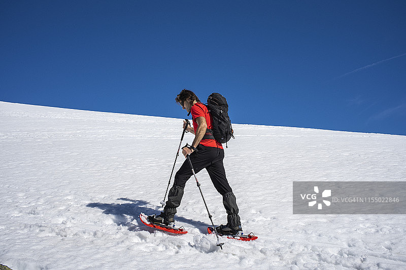 一个人穿着雪鞋在雪山上行走图片素材