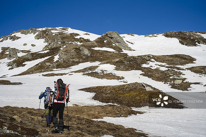 两个徒步旅行者在雪山上行走，荒野地区。图片素材