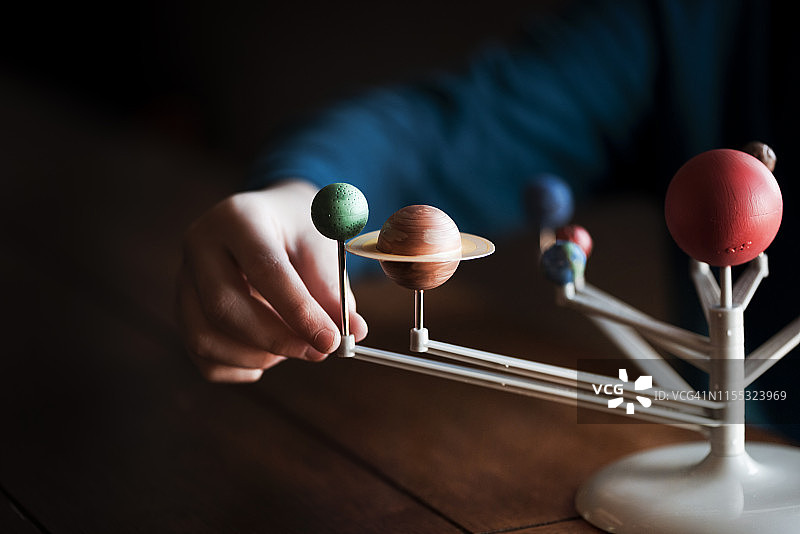 一个小男孩的手触摸着太阳系的模型图片素材